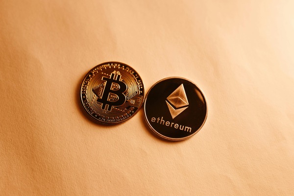 Bitcoin and Ethereum coins on a beige surface