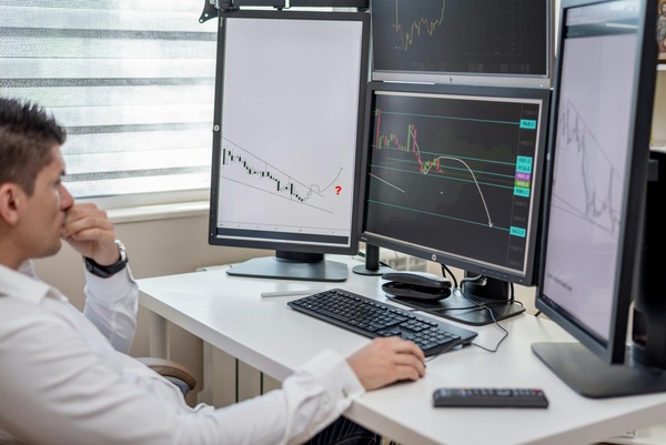 Trader analyzing charts on multiple monitors