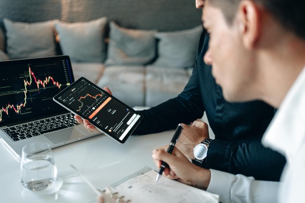 Two people reviewing charts on a tablet and laptop